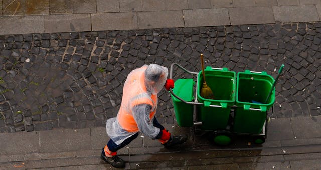 straatveger-in-de-regen-met-vuilniswagen