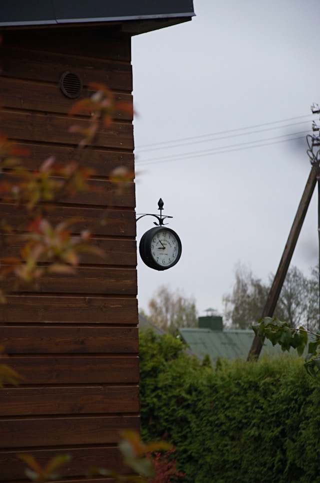Outdoor clock hanging on a wooden wall
