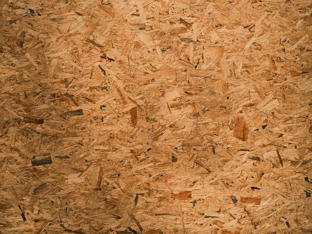Gedetailleerde close-up textuur van georiënteerde strandplaat (OSB) met rijke bruine tonen en ingewikkelde patronen.